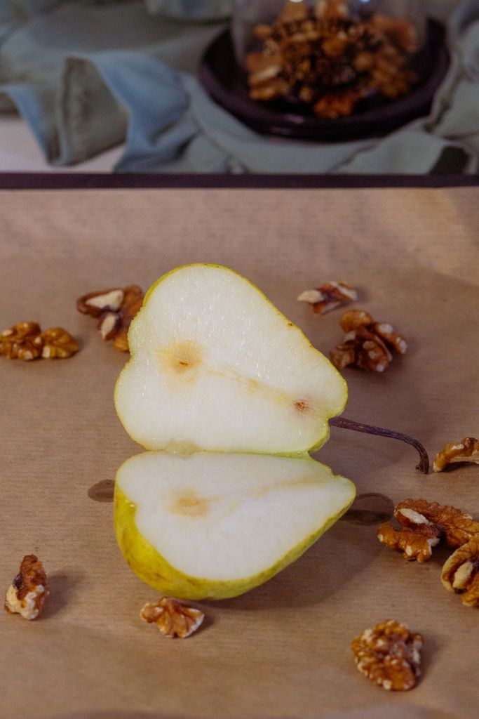 Sliced pear and walnuts on parchment, showcasing natural textures and colors.