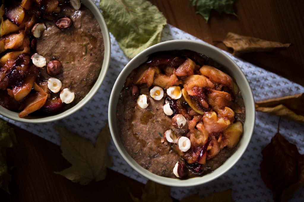 Warm autumn porridge topped with roasted fruits and hazelnuts, perfect for cozy fall mornings.